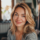 Femme souriante, cheveux blonds, intérieur lumineux.